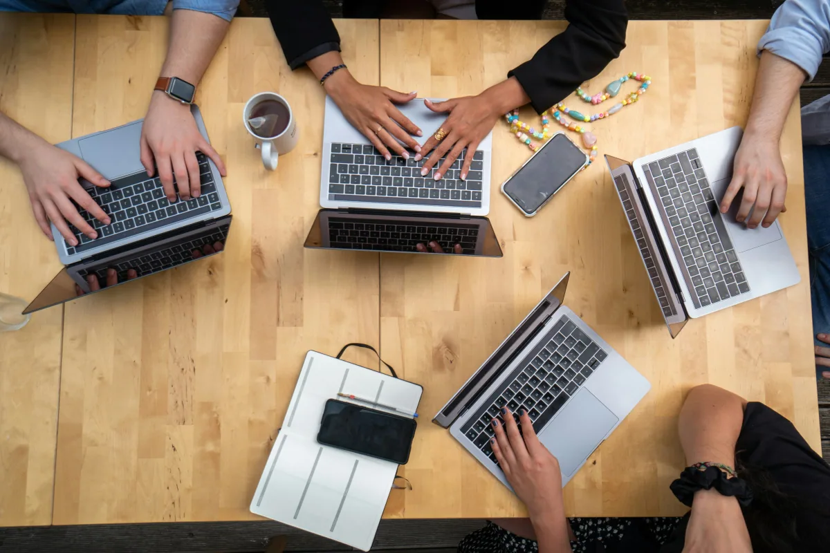 Persone al lavoro su computer portatili attorno a un tavolo
