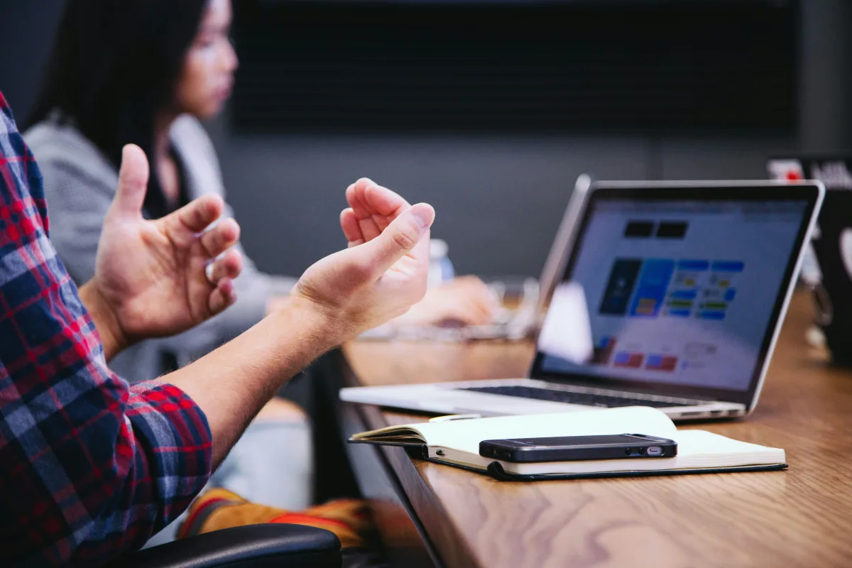 Confronto tra persone davanti a un computer e a un quaderno di lavoro